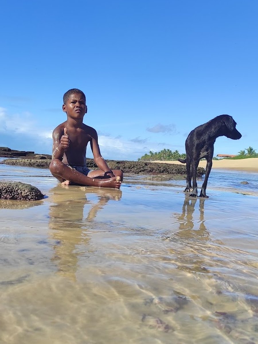 Menino e cachorro nas piscinas naturais rasas da Pedra do Nego