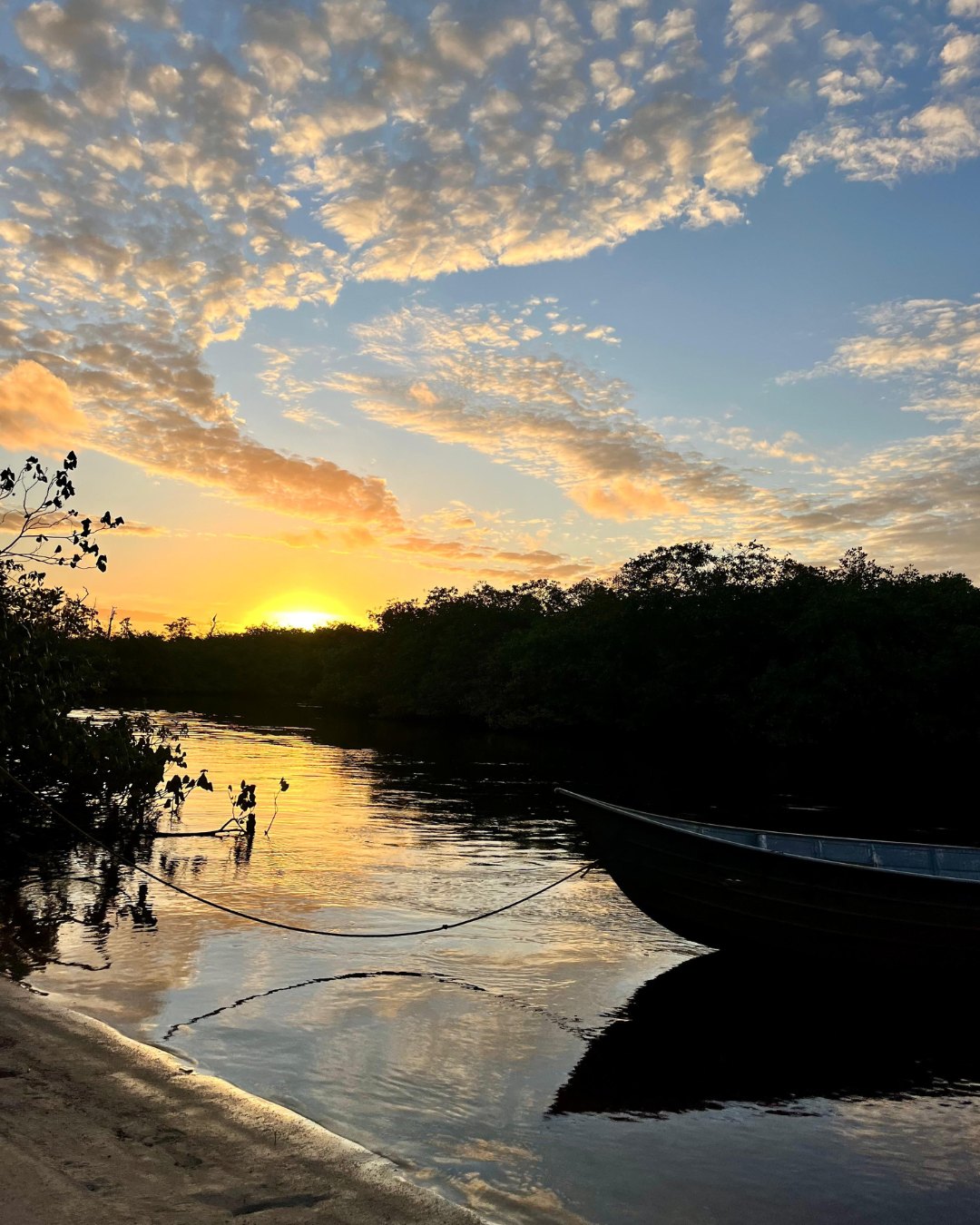 Pôr do sol dourado sobre o Rio Caraíva com um barco ancorado na Prainha