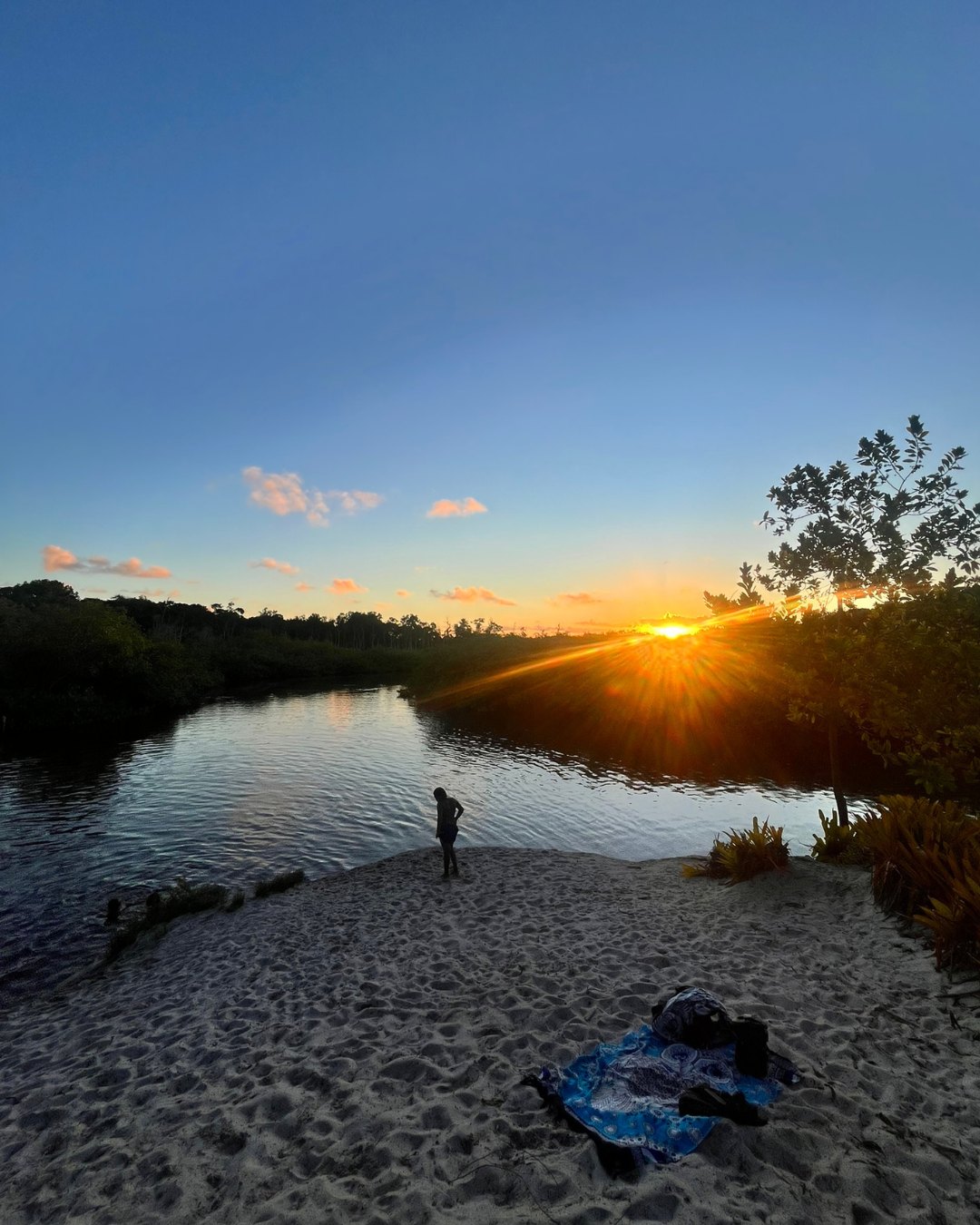 Pessoa no banco de areia da Prainha ao pôr do sol, à beira do rio
