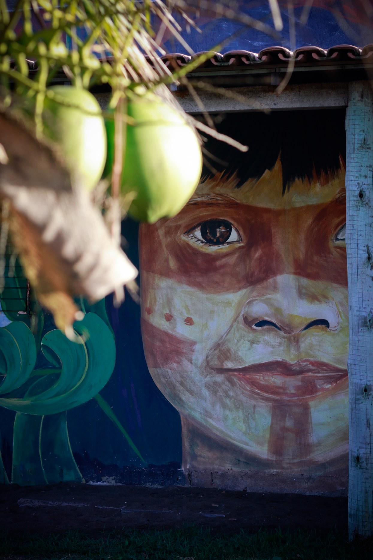 Mural pintado à mão de rosto de criança indígena na OCA Caraíva